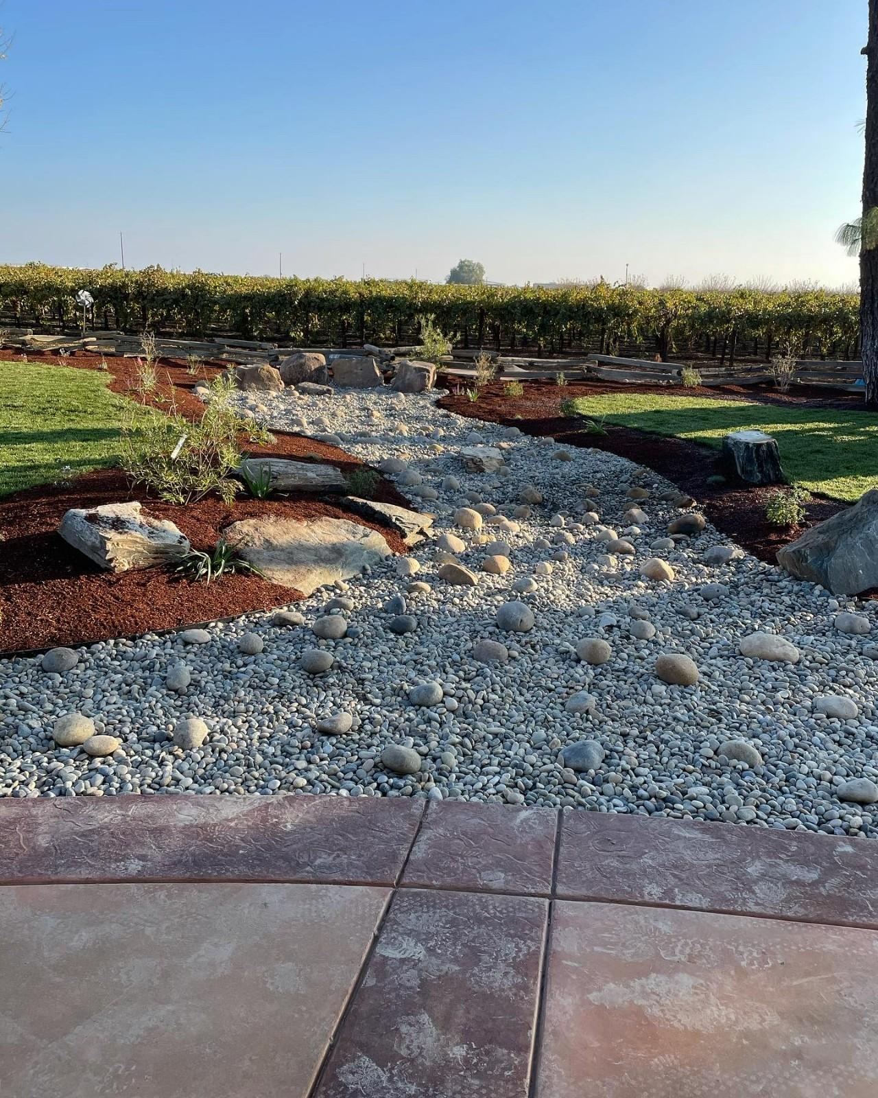 Dry creek bed landscape construction with river rock and boulders