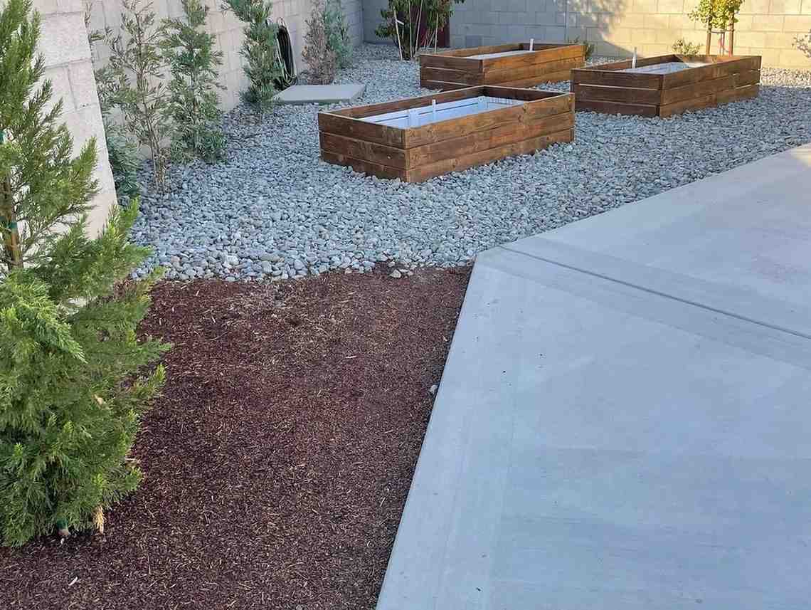 Backyard landscape construction with retaining planters and rock beds
