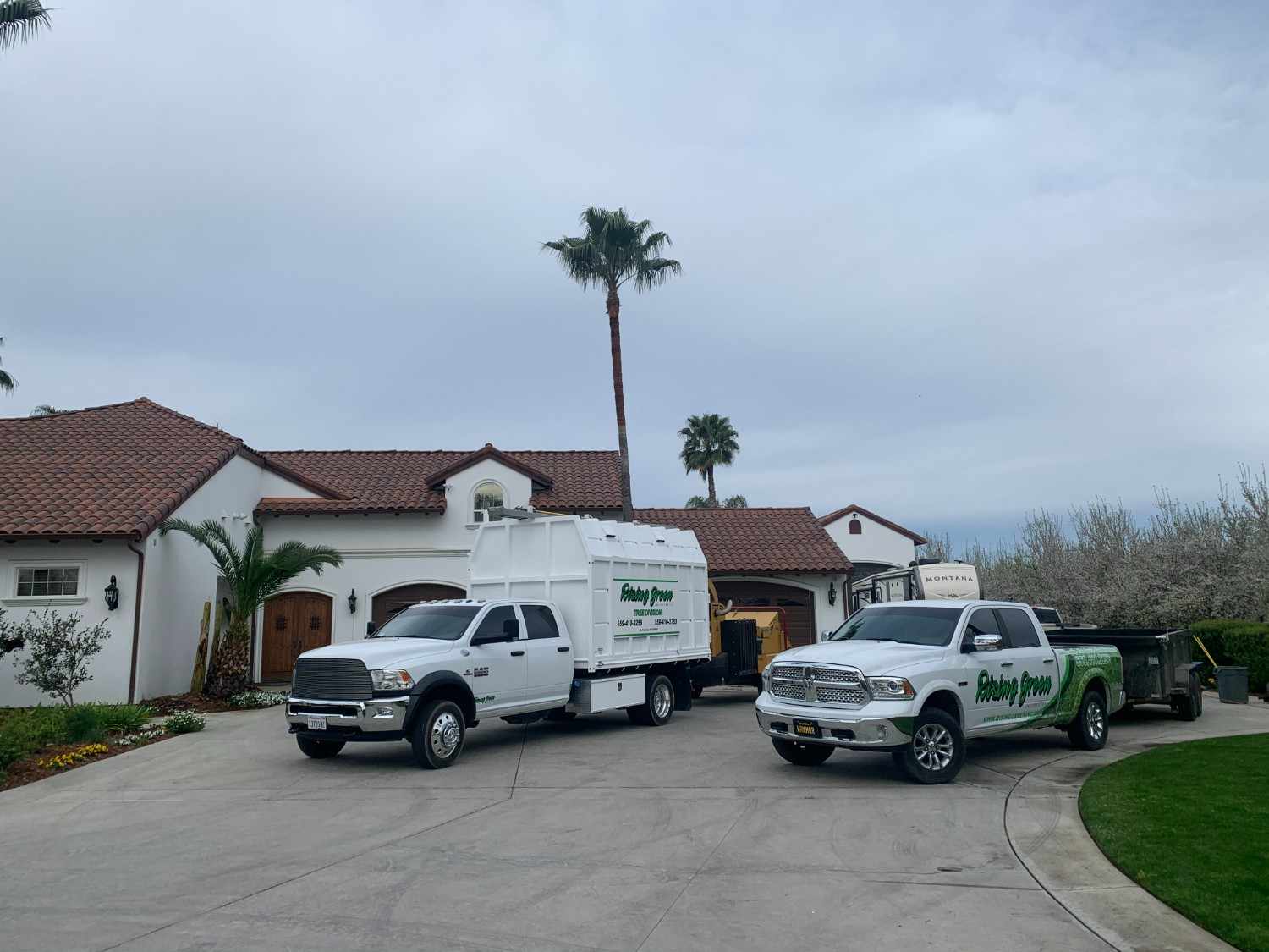 Two branded Rising Green Inc. trucks parked in a client's driveway